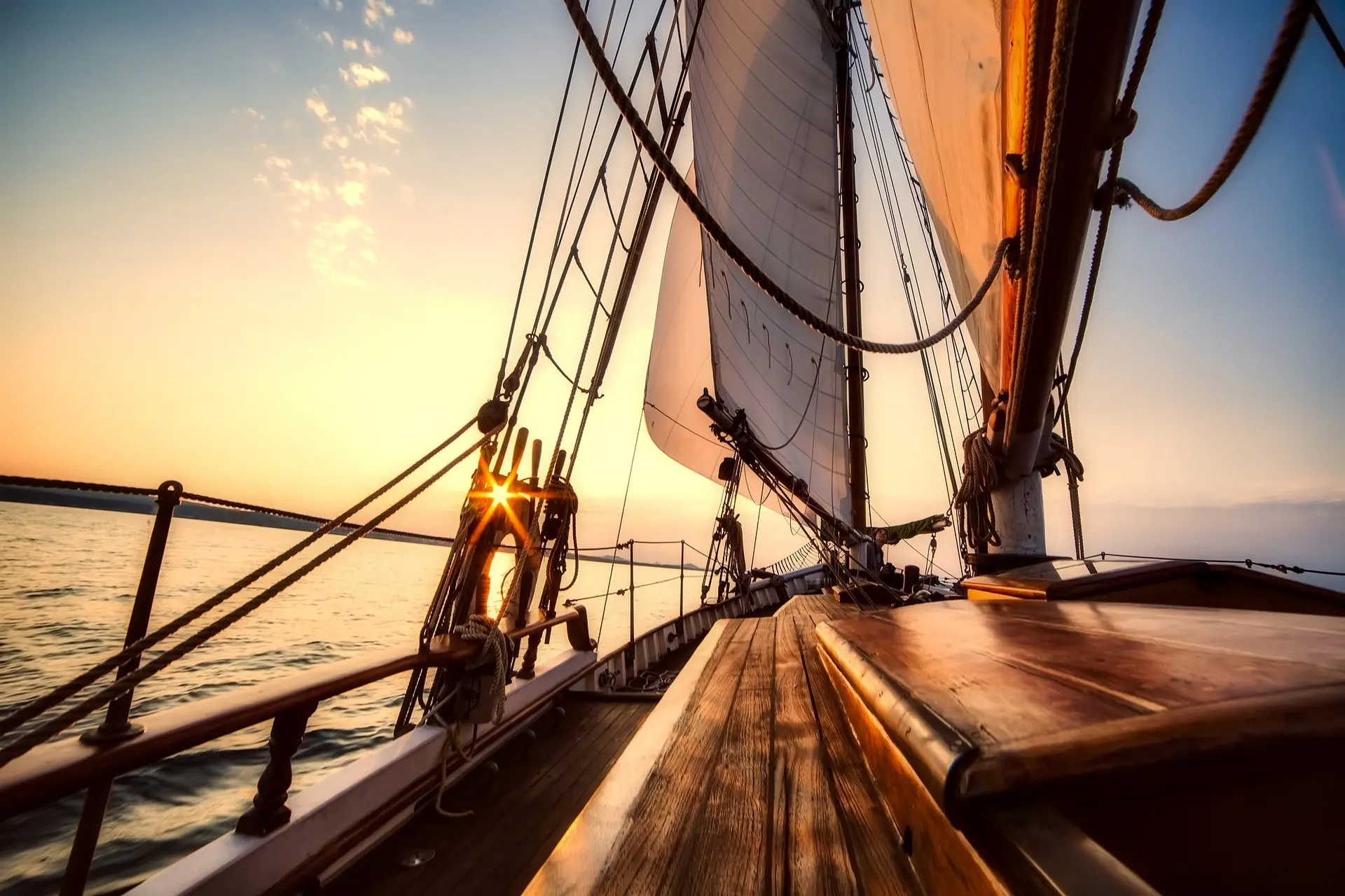 The deck of a tall ship under full sail, heading into the sunset