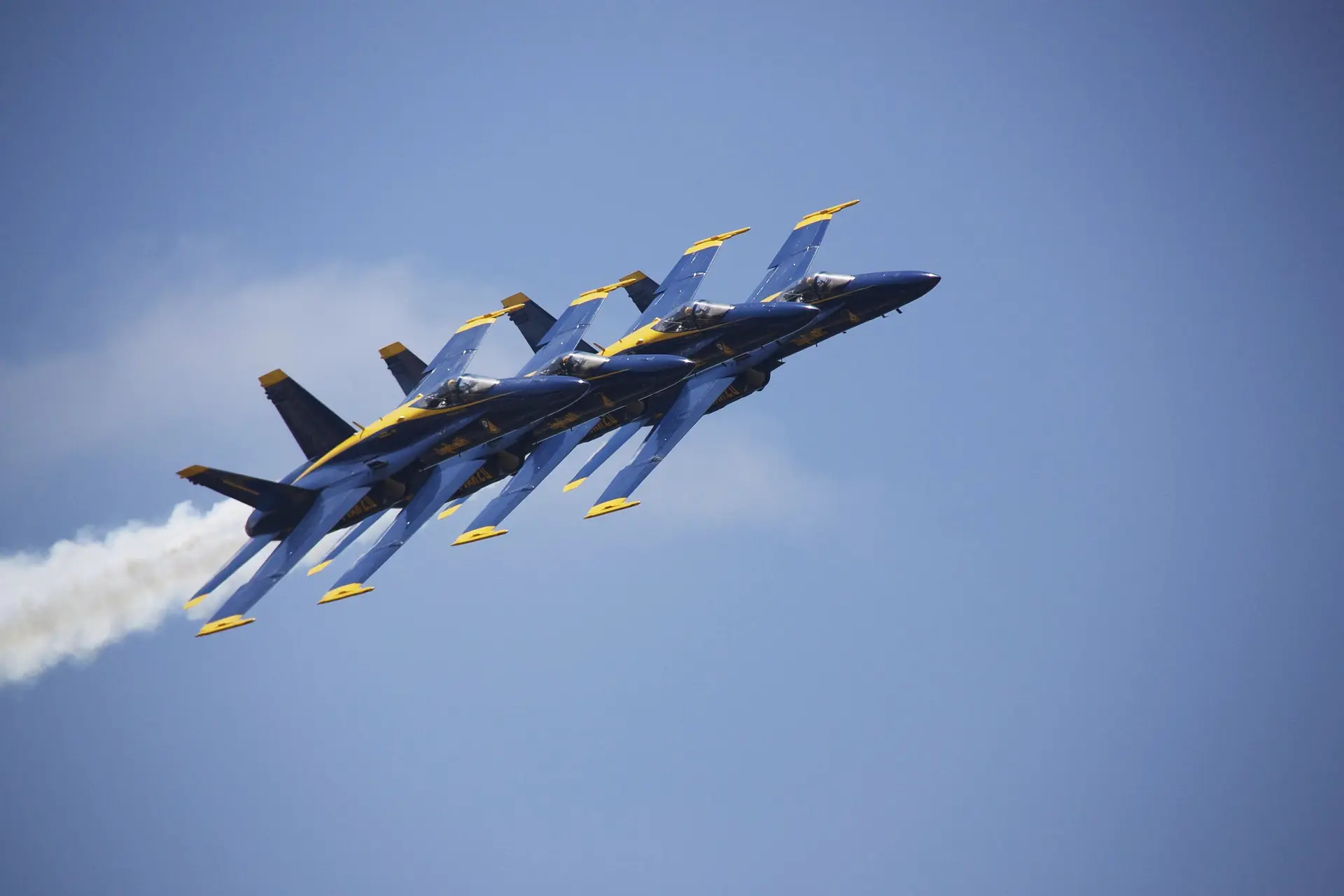 Four jets flying in tight formation across a clear sky